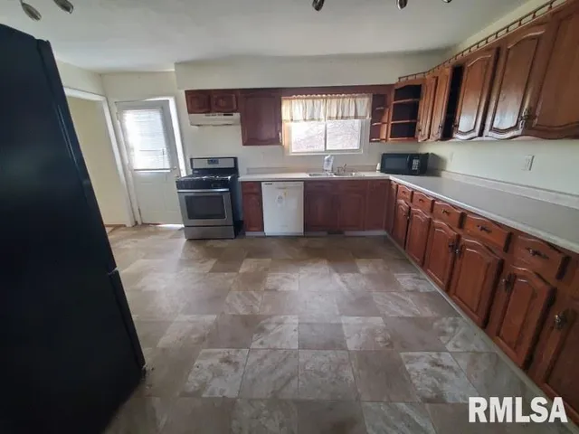 a kitchen with granite countertop a refrigerator and wooden cabinets