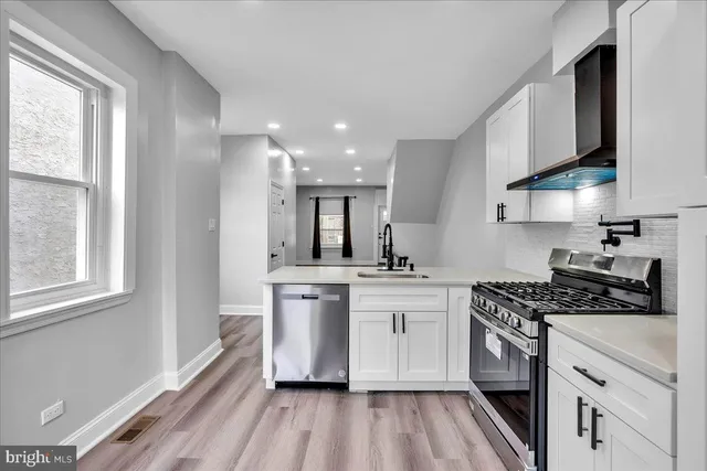 a kitchen with stainless steel appliances granite countertop a stove a sink dishwasher and a refrigerator with wooden floor