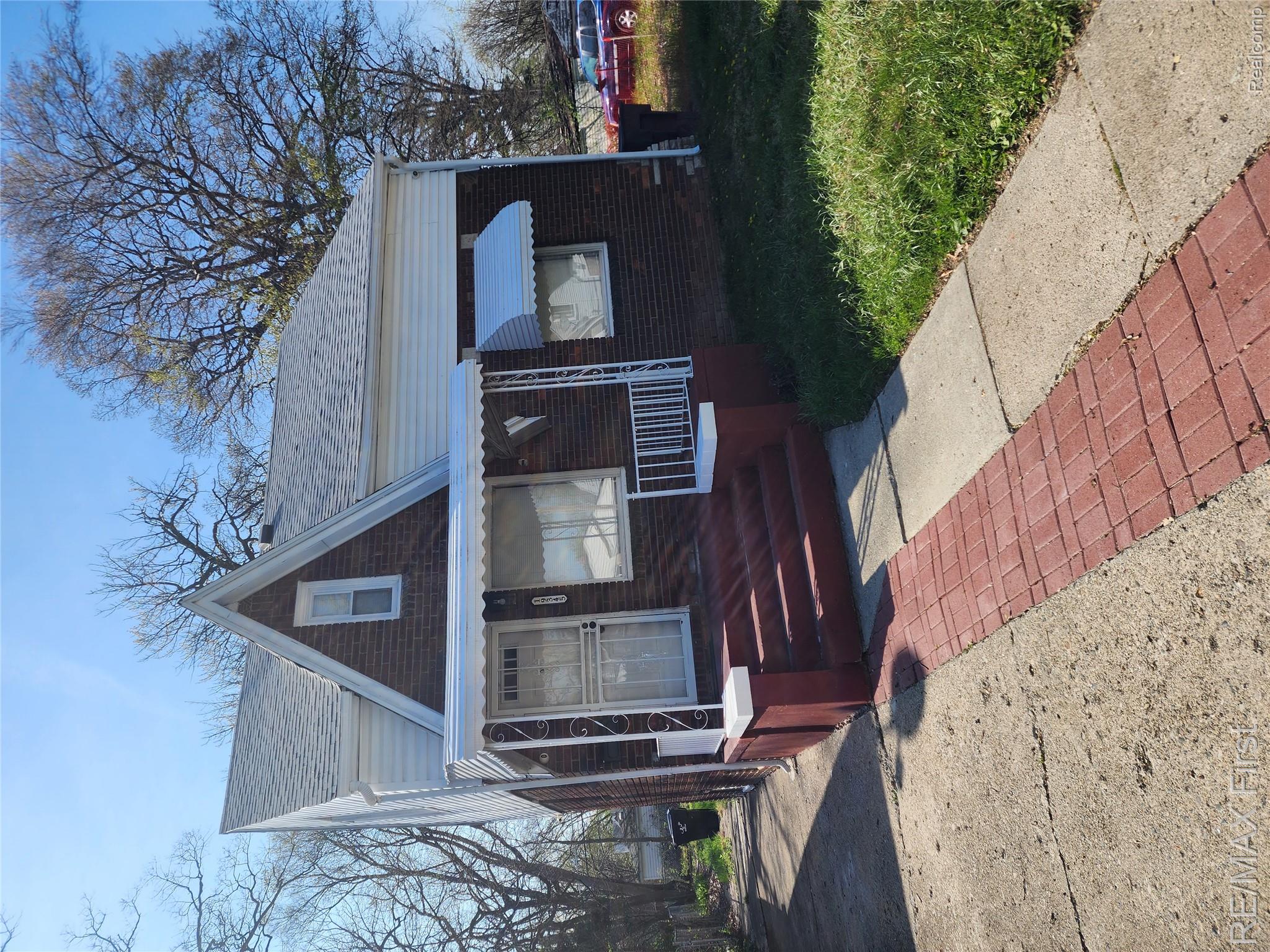 19345 Keystone Street Detroit, MI 48234 - Photo 1 of 15 Bungalow featuring covered porch, brick siding, a front yard, and roof with shingles