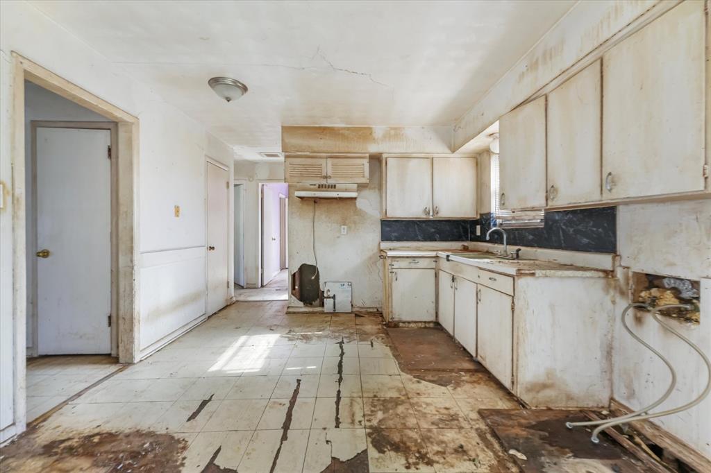12924 Mitchell Drive Balch Springs, TX 75180 - Photo 6 of 14 a kitchen with a sink stove and white cabinets