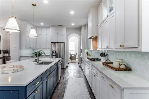 a kitchen with kitchen island granite countertop a sink a counter top space appliances and cabinets