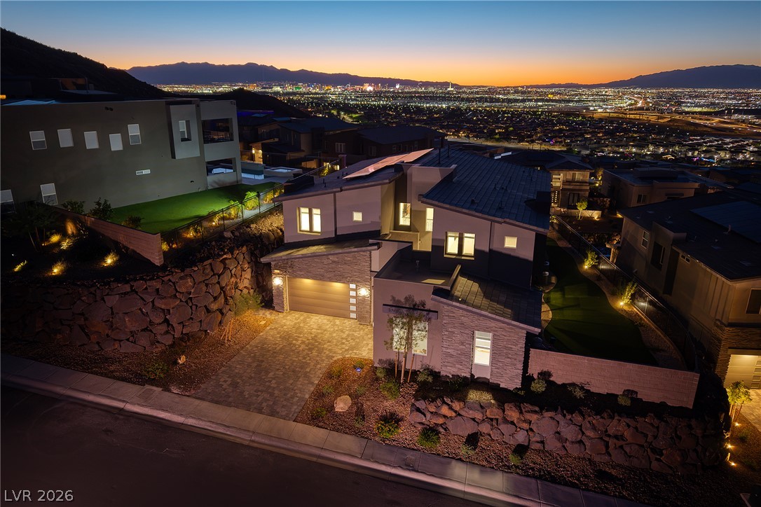 526 Riley Ridge Henderson, NV 89012 - Photo 1 of 10 Dramatic sunset hues silhouette a modern dwelling overlooking an illuminated cityscape.