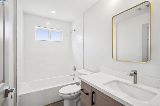 a view of a hallway with wooden floor and a bathroom