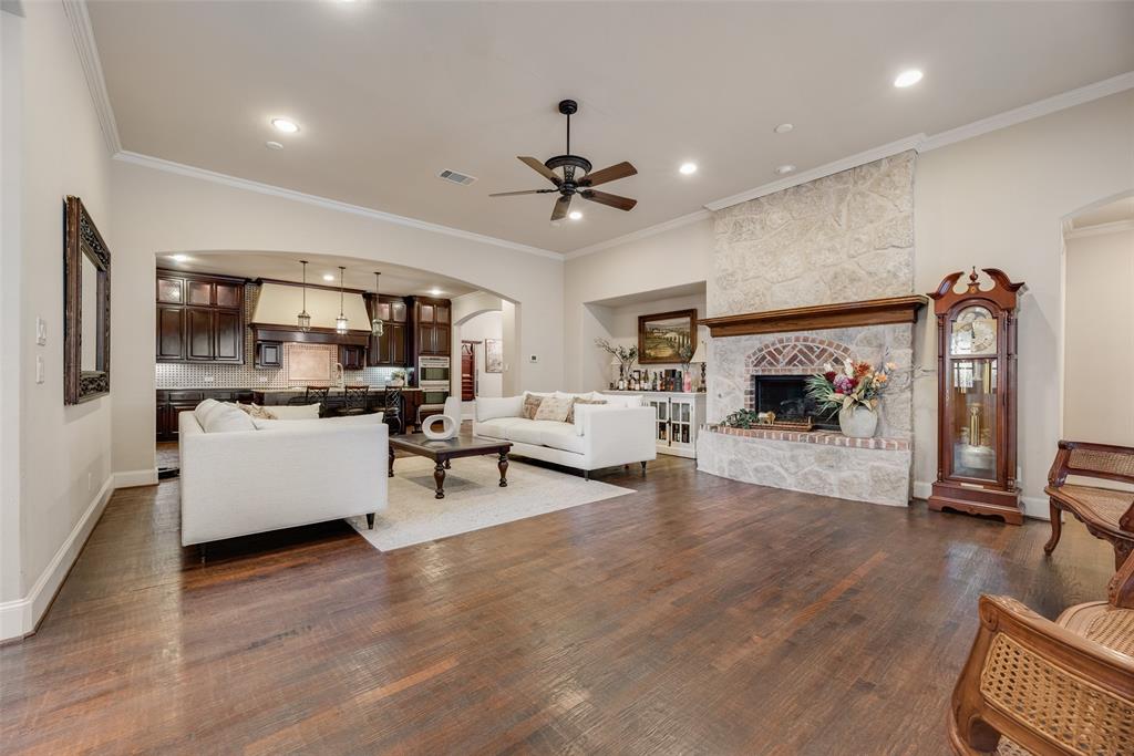 1909 Rising Star Drive Allen, TX 75013 - Photo 3 of 26 Living room featuring arched walkways, dark wood-style floors, a large fireplace, crown molding, and recessed lighting