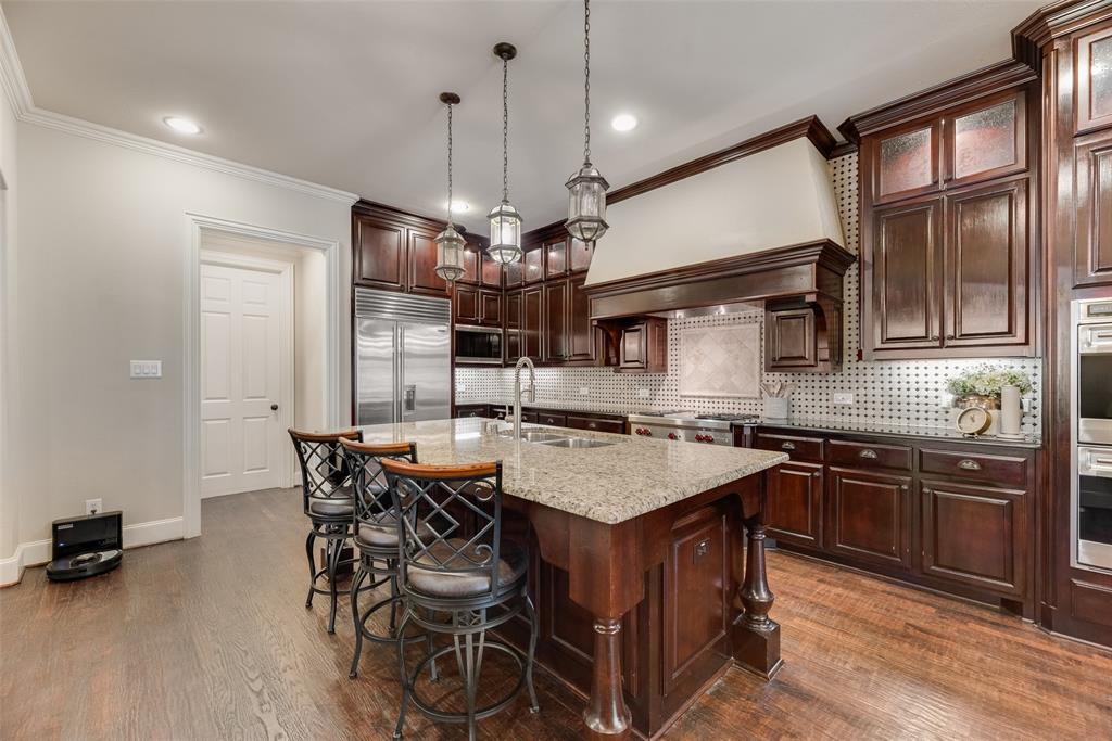 1909 Rising Star Drive Allen, TX 75013 - Photo 5 of 26 Kitchen with an island with sink, built in appliances, a kitchen bar, dark wood-style flooring, and ornamental molding