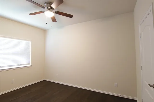 an empty room with a window and a fan