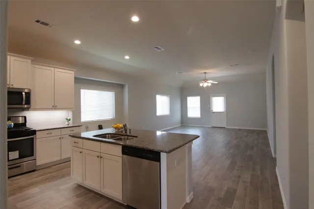 a kitchen with granite countertop stove sink and cabinets