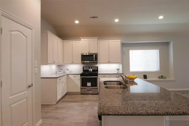 a kitchen with stainless steel appliances granite countertop a sink stove and refrigerator