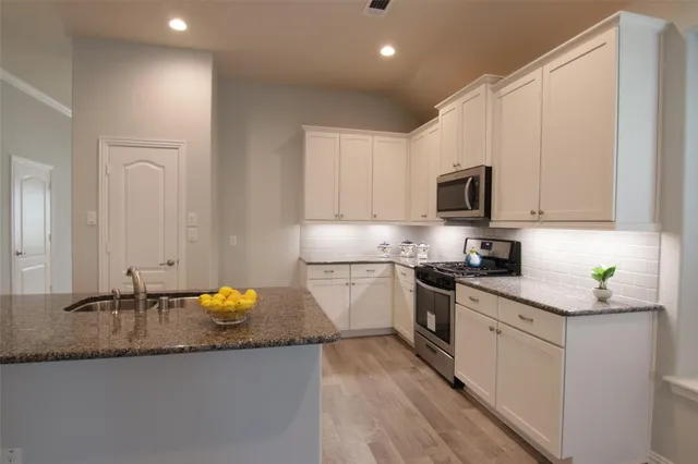a kitchen with granite countertop white cabinets and white appliances
