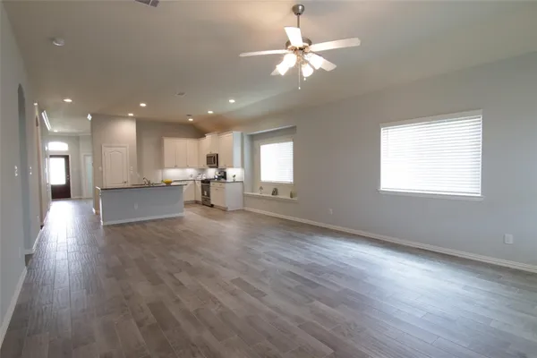 an empty room with wooden floor and windows