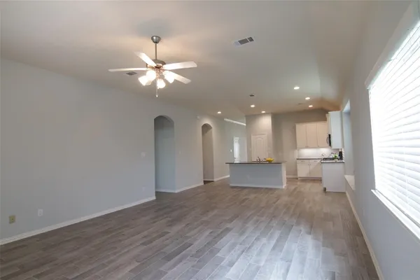 a view of an empty room with a window and wooden floor
