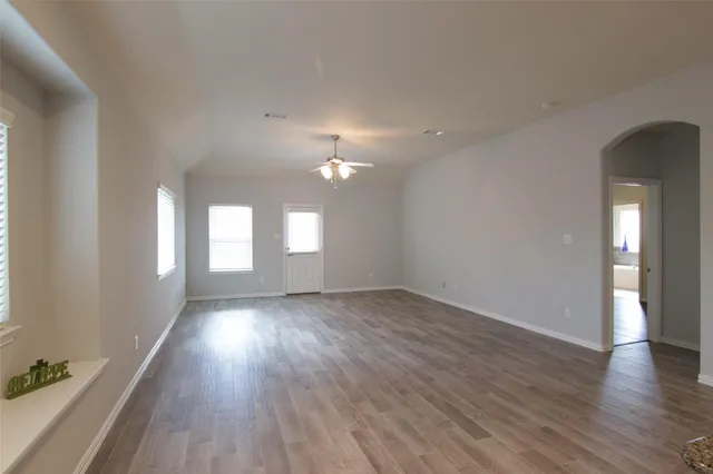 an empty room with wooden floor and windows