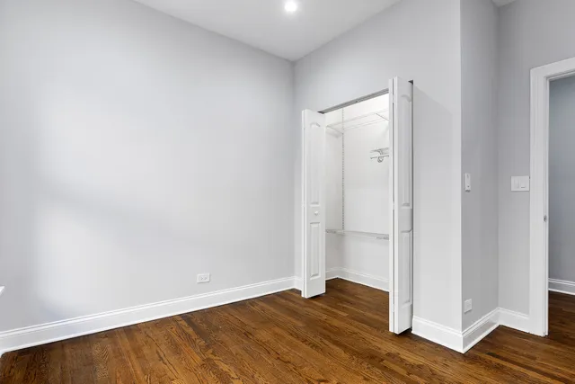 a view of an empty room with wooden floor and closet