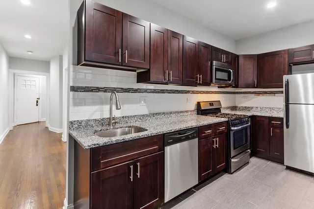 a kitchen with stainless steel appliances granite countertop wooden cabinets a stove top oven a sink and dishwasher