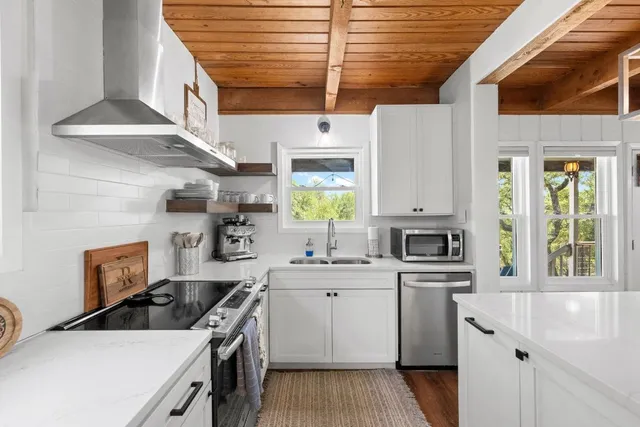 a kitchen with stainless steel appliances a white stove top oven a sink a chimney and cabinets