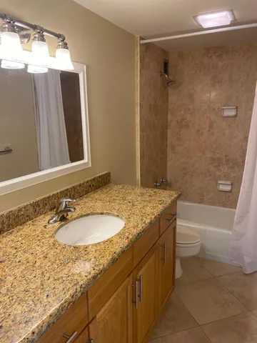 a bathroom with a granite countertop sink a mirror and a bathtub