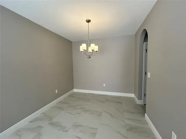 a view of an empty room with chandelier and a window