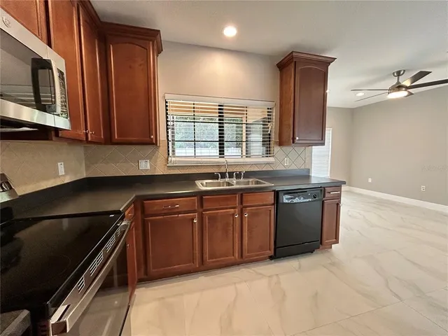 a kitchen with granite countertop a sink cabinets and stainless steel appliances