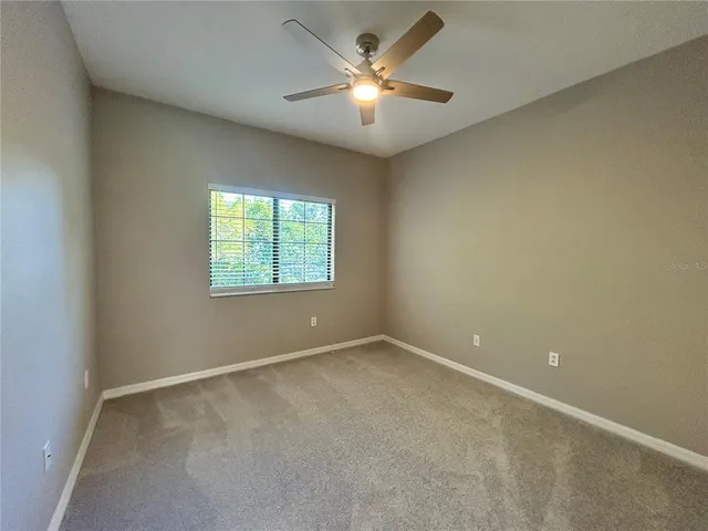 an empty room with a window and a fan