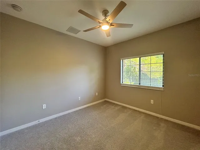 an empty room with windows and fan