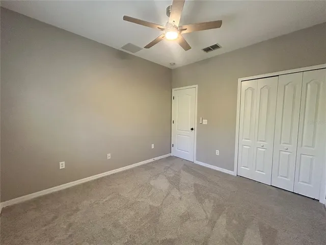 an empty room with closet and a ceiling fan
