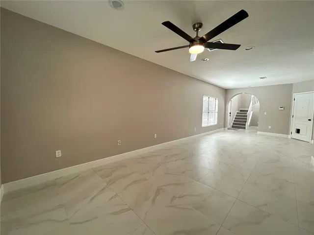 an empty room with ceiling fan and windows
