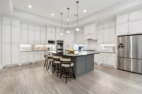 a kitchen with stainless steel appliances granite countertop a refrigerator a stove top oven a sink dishwasher and white cabinets with wooden floor
