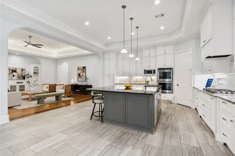 a kitchen with stainless steel appliances kitchen island granite countertop a stove top oven a sink a dining table and chairs with wooden floor