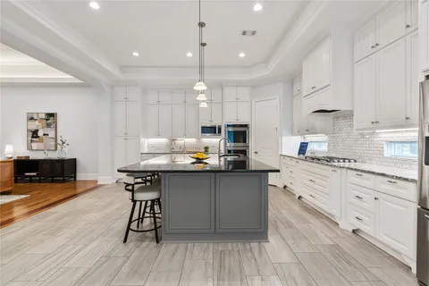 a kitchen with stainless steel appliances granite countertop a table chairs sink and cabinets