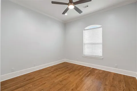 an empty room with wooden floor fan and windows