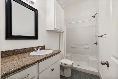 a bathroom with a granite countertop sink a toilet and a mirror
