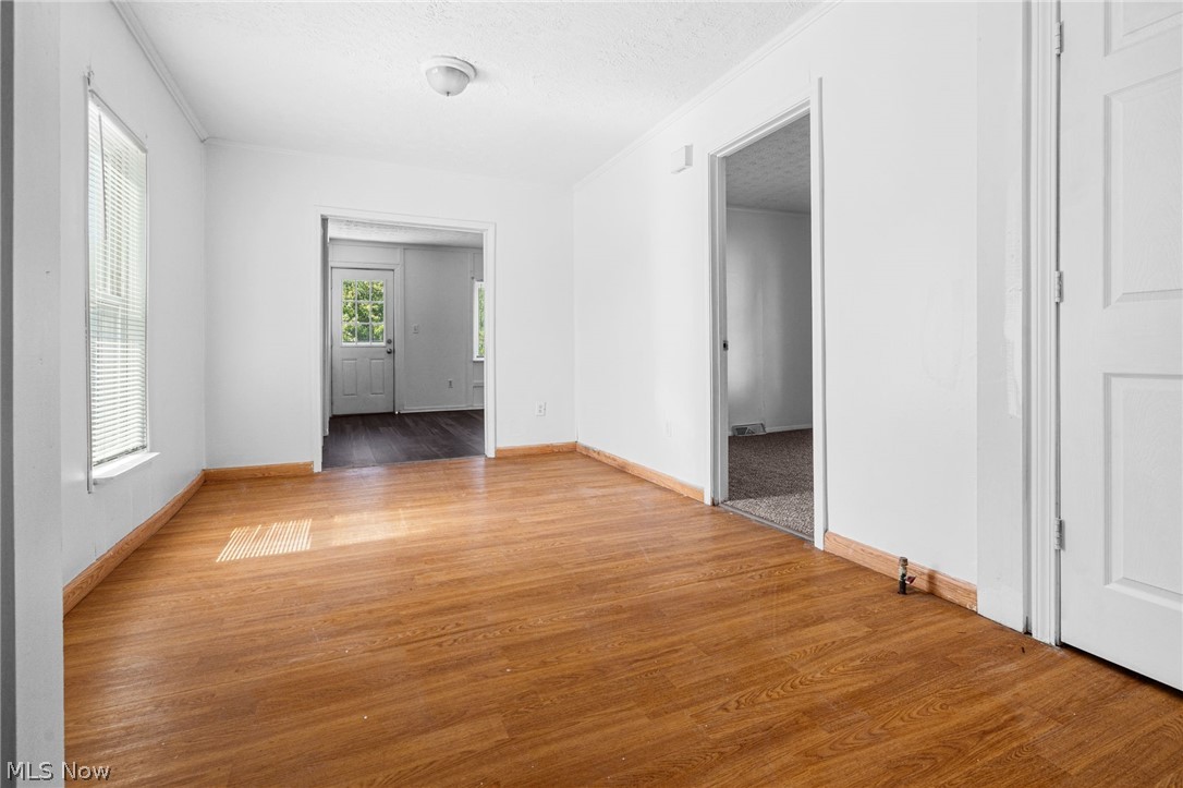 2387 29th Street Southwest Akron, OH 44314 - Photo 20 of 24 Spare room featuring a textured ceiling, light wood-type flooring, and ornamental molding