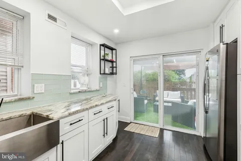 a kitchen with stainless steel appliances granite countertop a refrigerator a sink and white cabinets with wooden floor