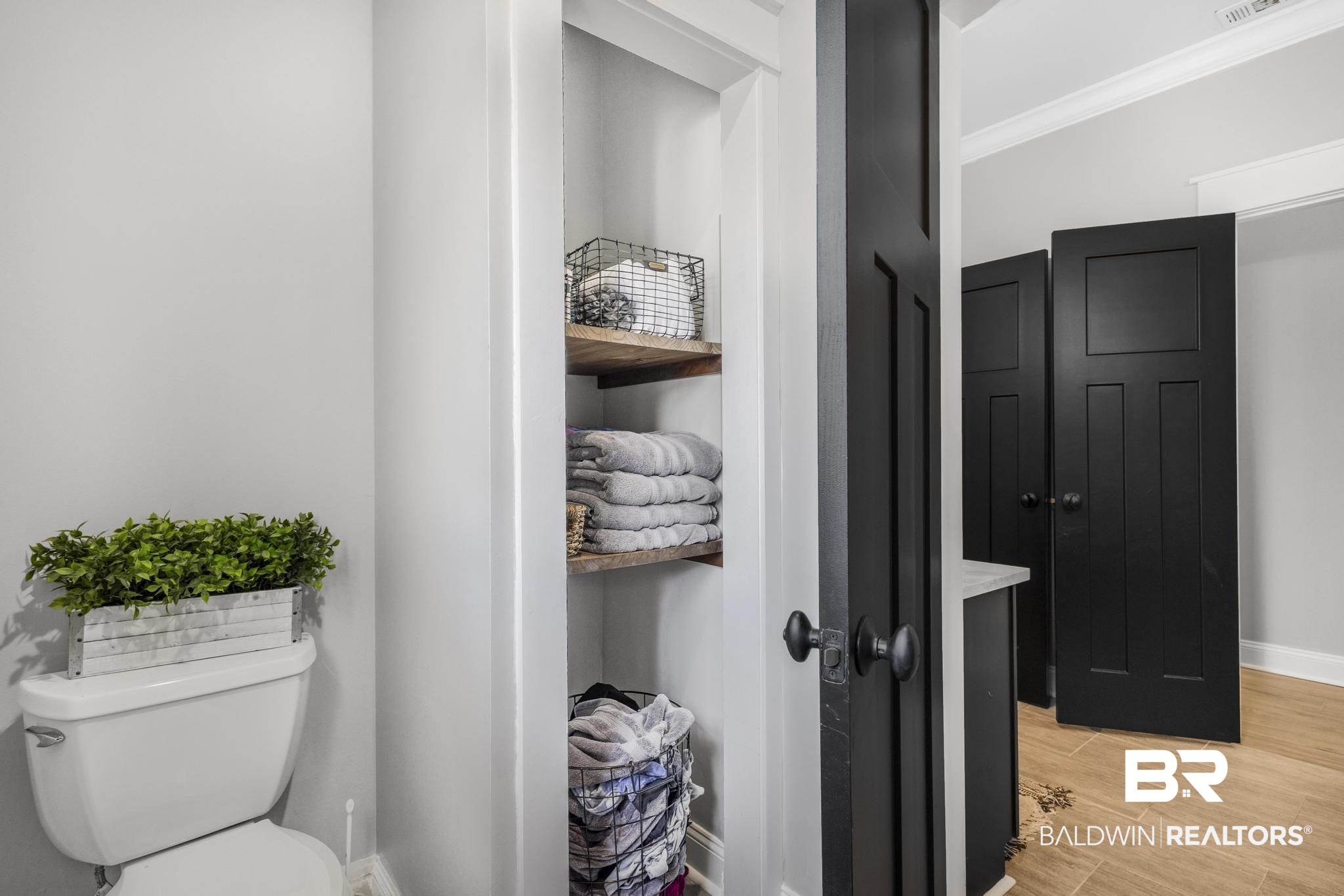 83 Caisson Trace Daphne, AL 36527 - Photo 48 of 63 Recessed shelving with wood-finish shelves, light gray walls, white baseboards, and black interior doors with matte black hardware