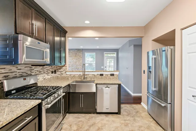 a kitchen with stainless steel appliances granite countertop a stove a sink and a refrigerator