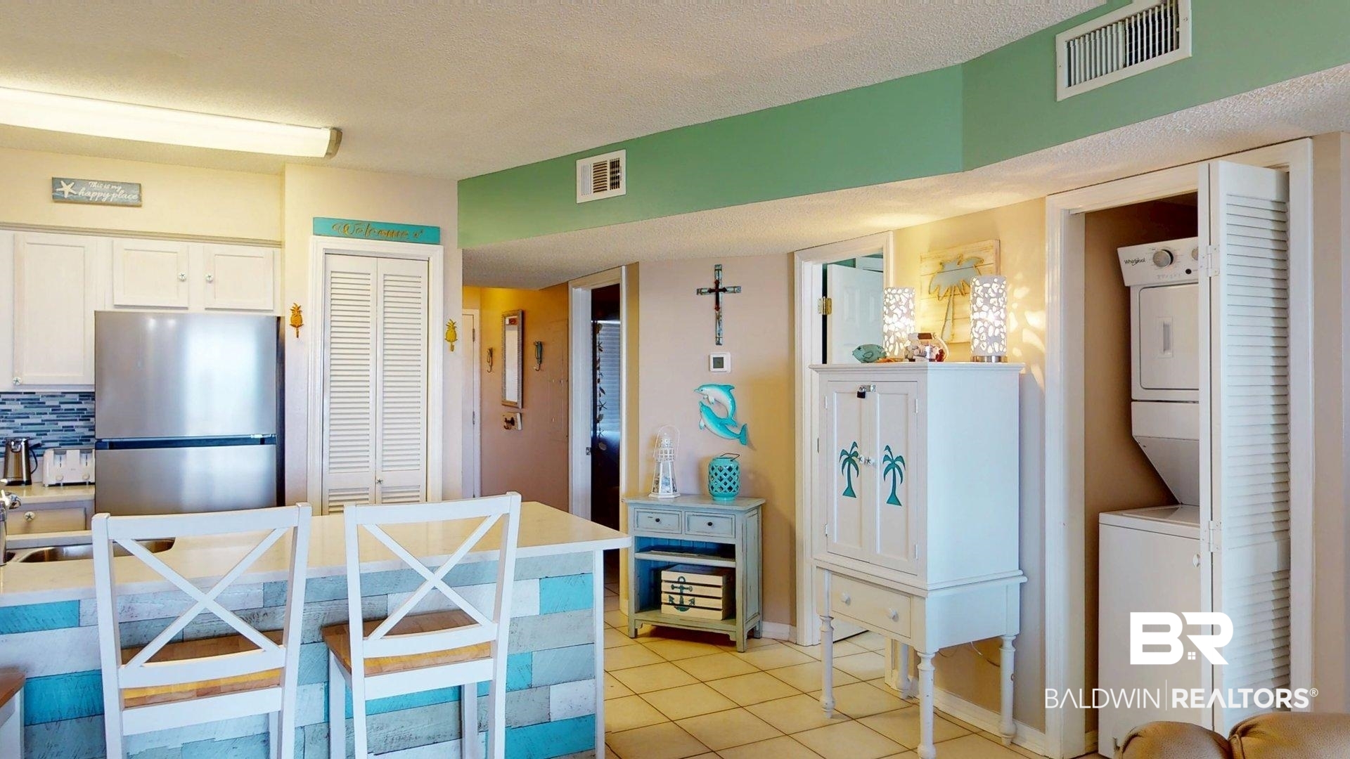 645 Plantation Road, Unit 6503 Gulf Shores, AL 36542 - Photo 20 of 53 Kitchen with light tile patterned floors, freestanding refrigerator, a breakfast bar area, white cabinetry, and a textured ceiling