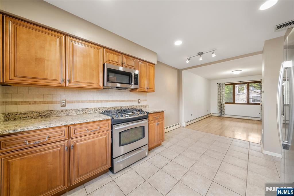 140 Allwood Road, Unit C Clifton, NJ 07012 - Photo 15 of 31 a kitchen with granite countertop a stove top oven a sink dishwasher and cabinets with wooden floor