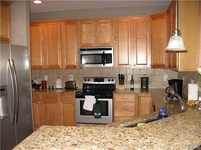 5916 Chivalry Court Raleigh, NC 27612 - Photo 4 of 25 Upgraded Kitchen with Granite Countertops, New Stainless Appliances (Smooth-top Range, Microwave, Dishwasher, Refrigerator), 42" Cabinets, and Tile Backsplash.