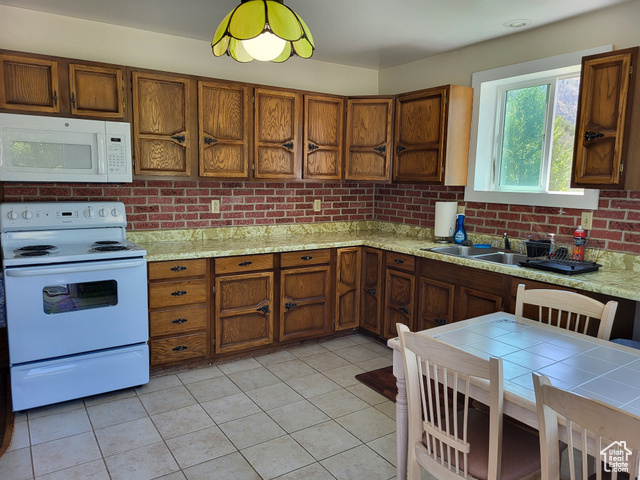 1406 South Bartholomew Cyn Road Springville, UT 84663 - Photo 16 of 19 Kitchen featuring white appliances, light countertops, and brown cabinetry