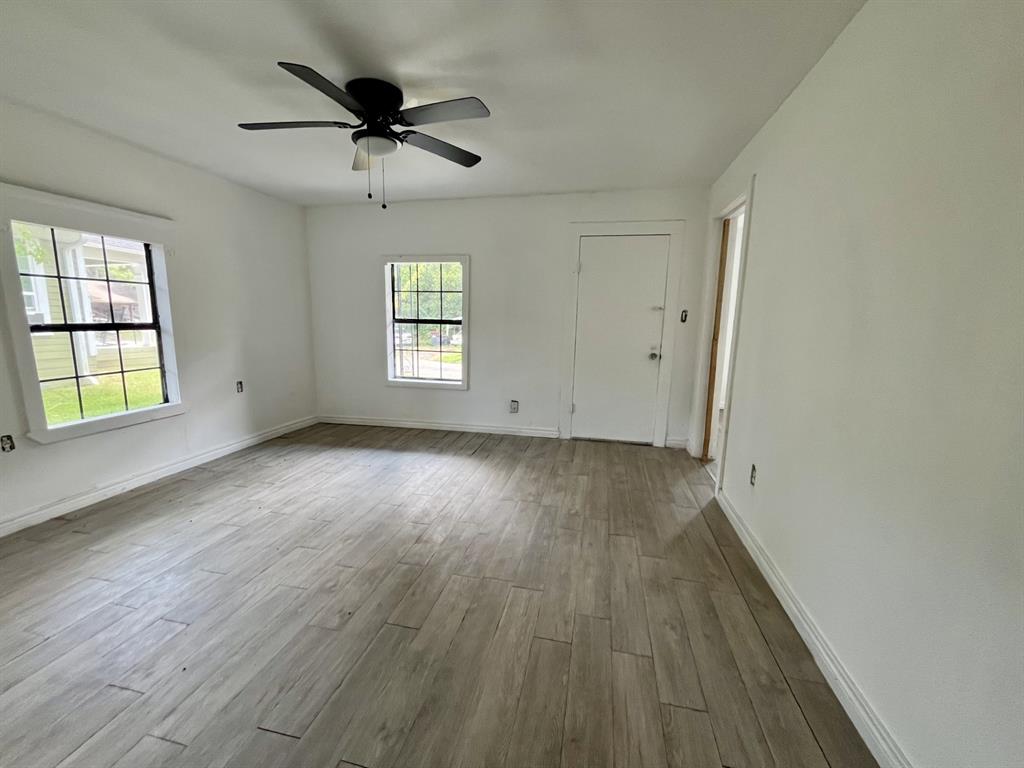 1037 Cedar Street Paris, TX 75460 - Photo 4 of 13 an empty room with wooden floor chandelier fan and windows