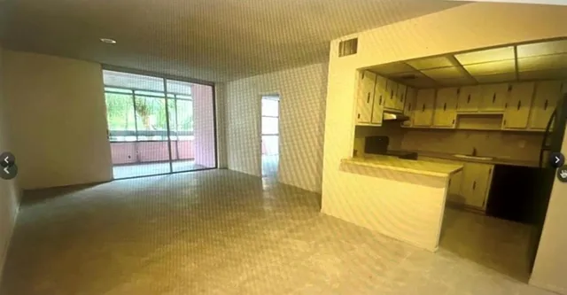 a view of empty room with a kitchen