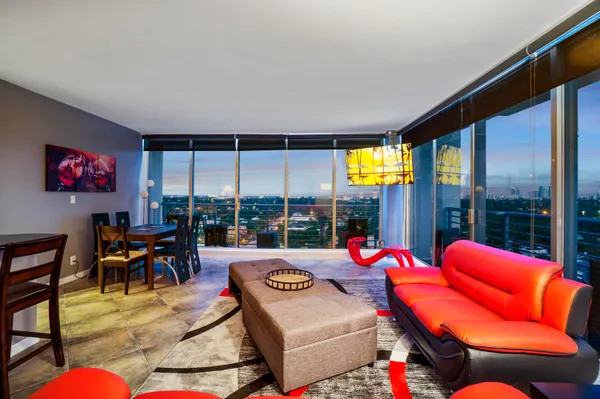 a living room with furniture kitchen view and a large window