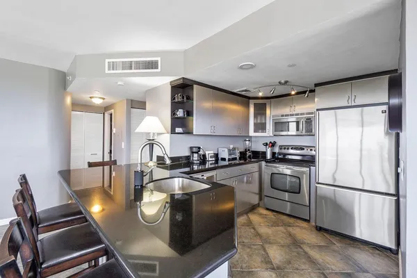 a kitchen with stainless steel appliances granite countertop a refrigerator a stove a sink dishwasher a dining table and chairs with wooden floor