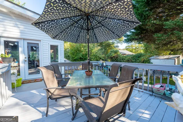 a patio with wooden floor a yard a table and chairs