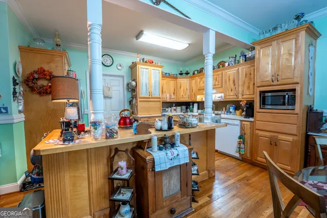 a kitchen with a refrigerator a stove a sink dishwasher and a fireplace with wooden floor