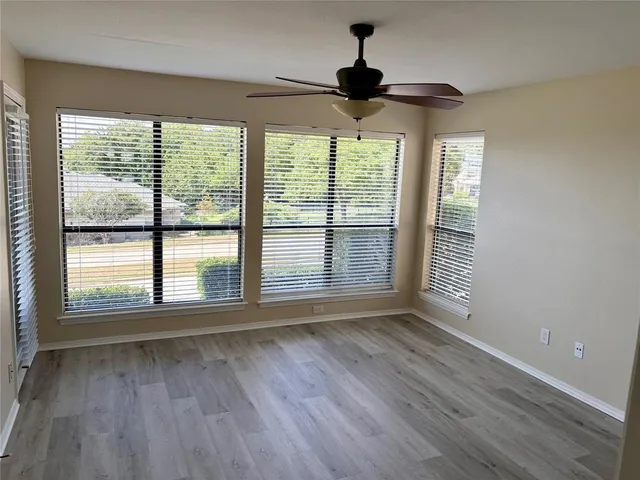 a view of an empty room with a window and wooden floor