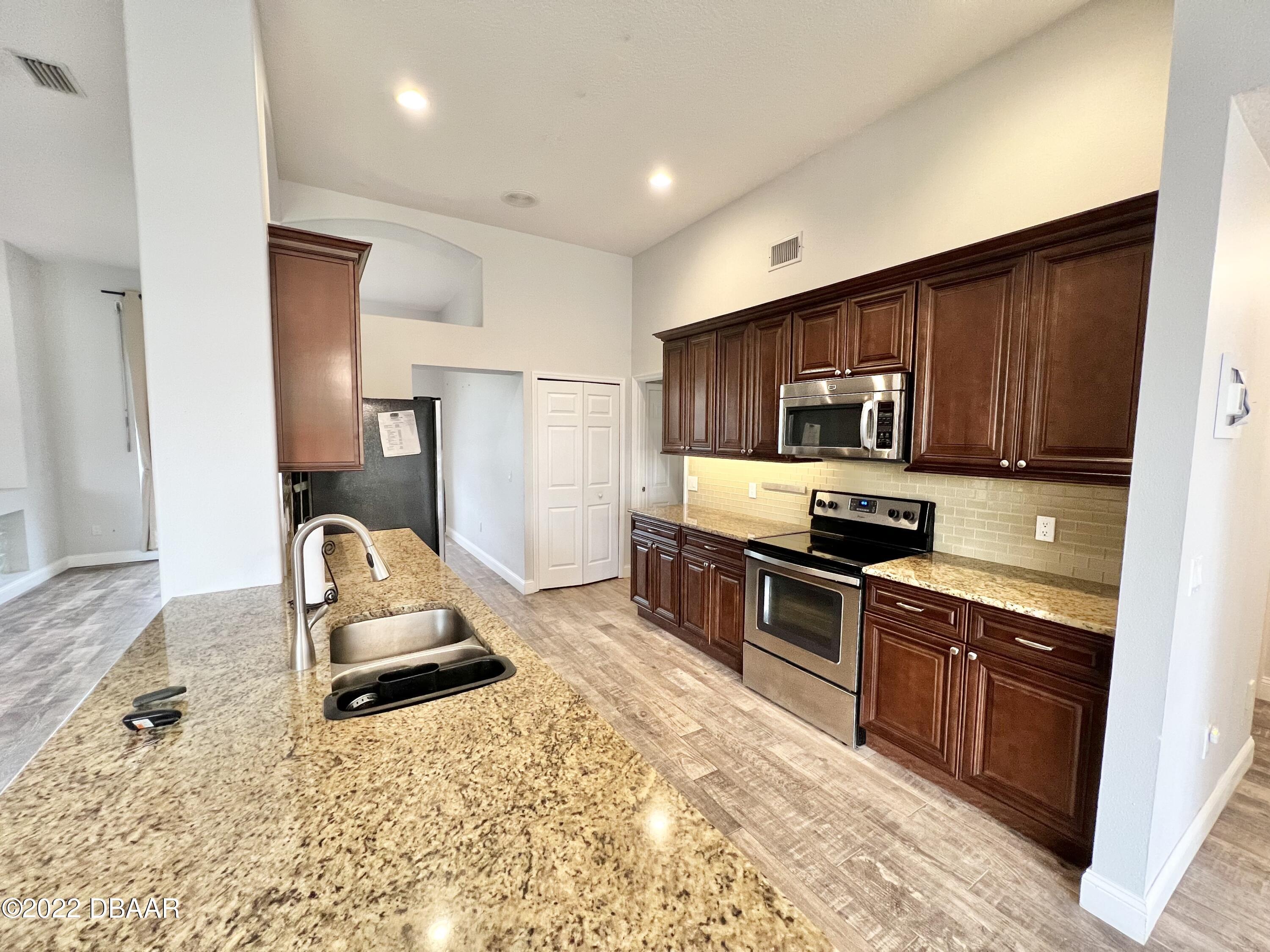 75 Creek Bluff Way Ormond Beach, FL 32174 - Photo 6 of 20 a kitchen with stainless steel appliances granite countertop a stove refrigerator sink and microwave