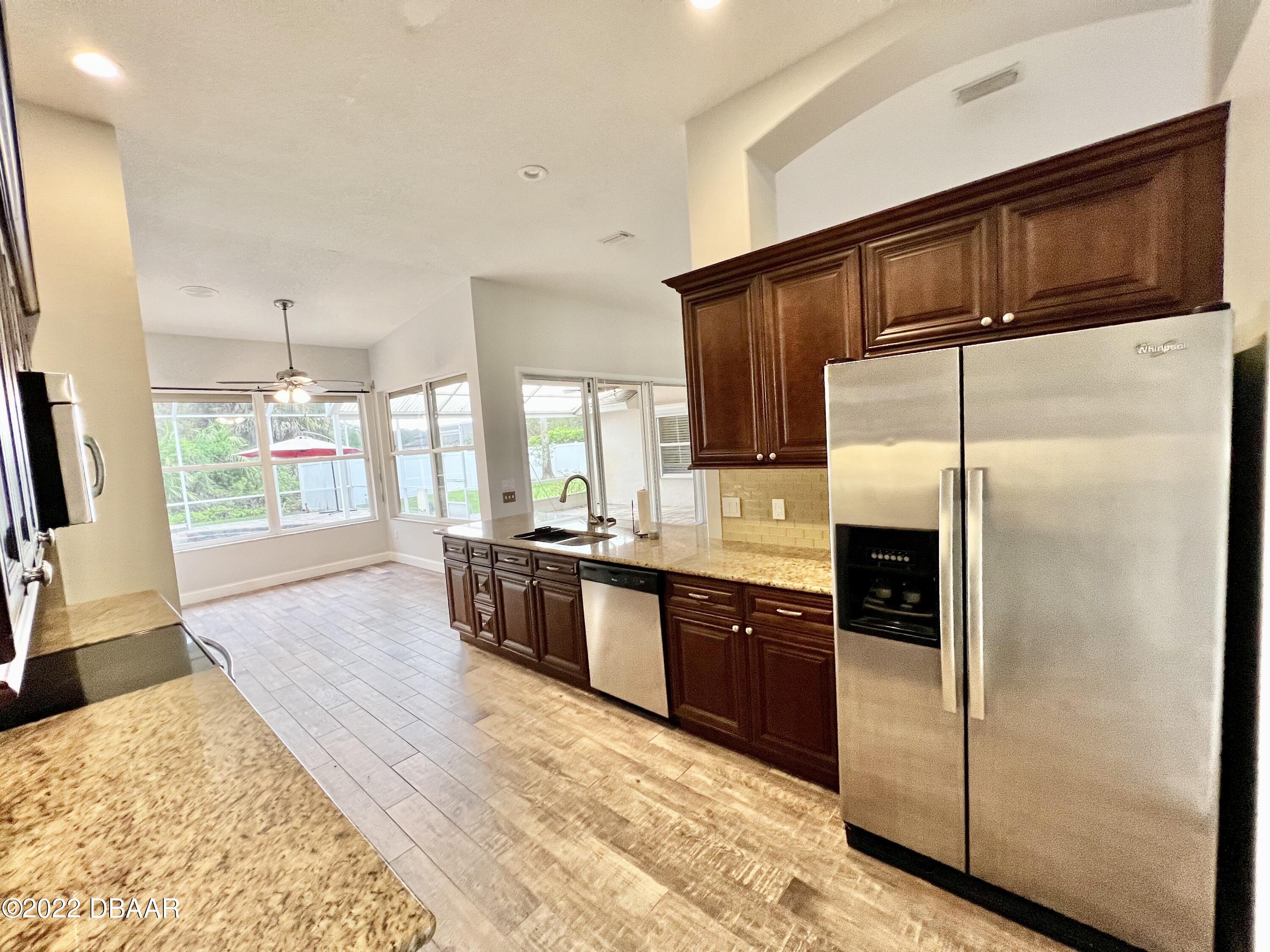 75 Creek Bluff Way Ormond Beach, FL 32174 - Photo 8 of 20 a kitchen with stainless steel appliances granite countertop a refrigerator a sink a stove a oven with wooden cabinets and floor