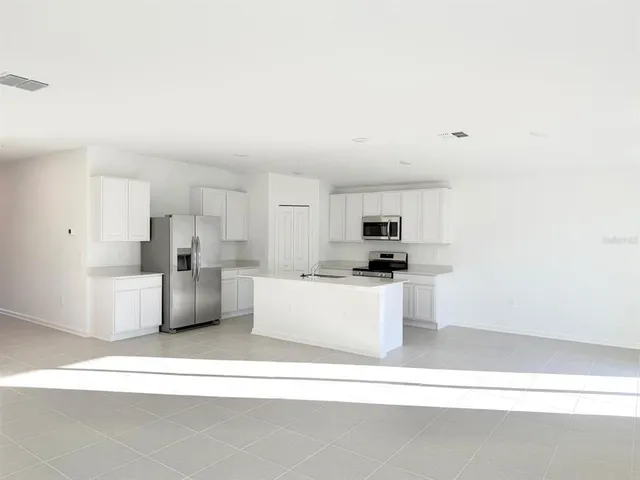 a living room with stainless steel appliances kitchen island sink refrigerator and fireplace