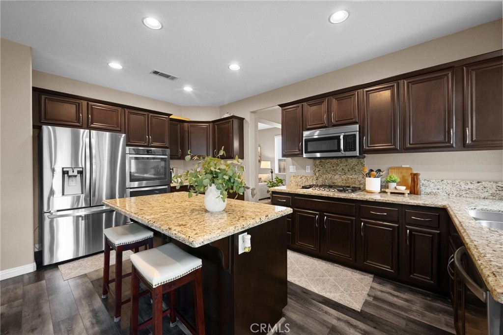 7220 Cumberland Place Rancho Cucamonga, CA 91739 - Photo 12 of 41 Chef-inspired kitchen featuring espresso cabinetry, granite countertops, stainless steel appliances, and a large center island.